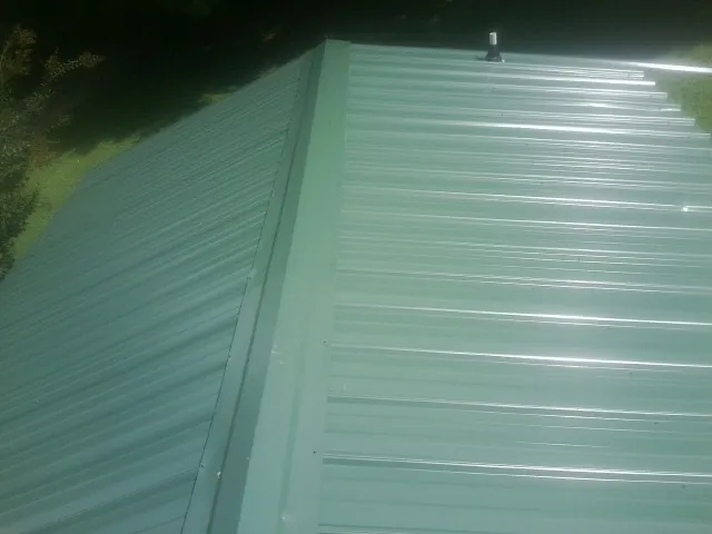 New green metal panels meeting at the ridge of a roof — Flat Roof Repair work by our crew in Dundas