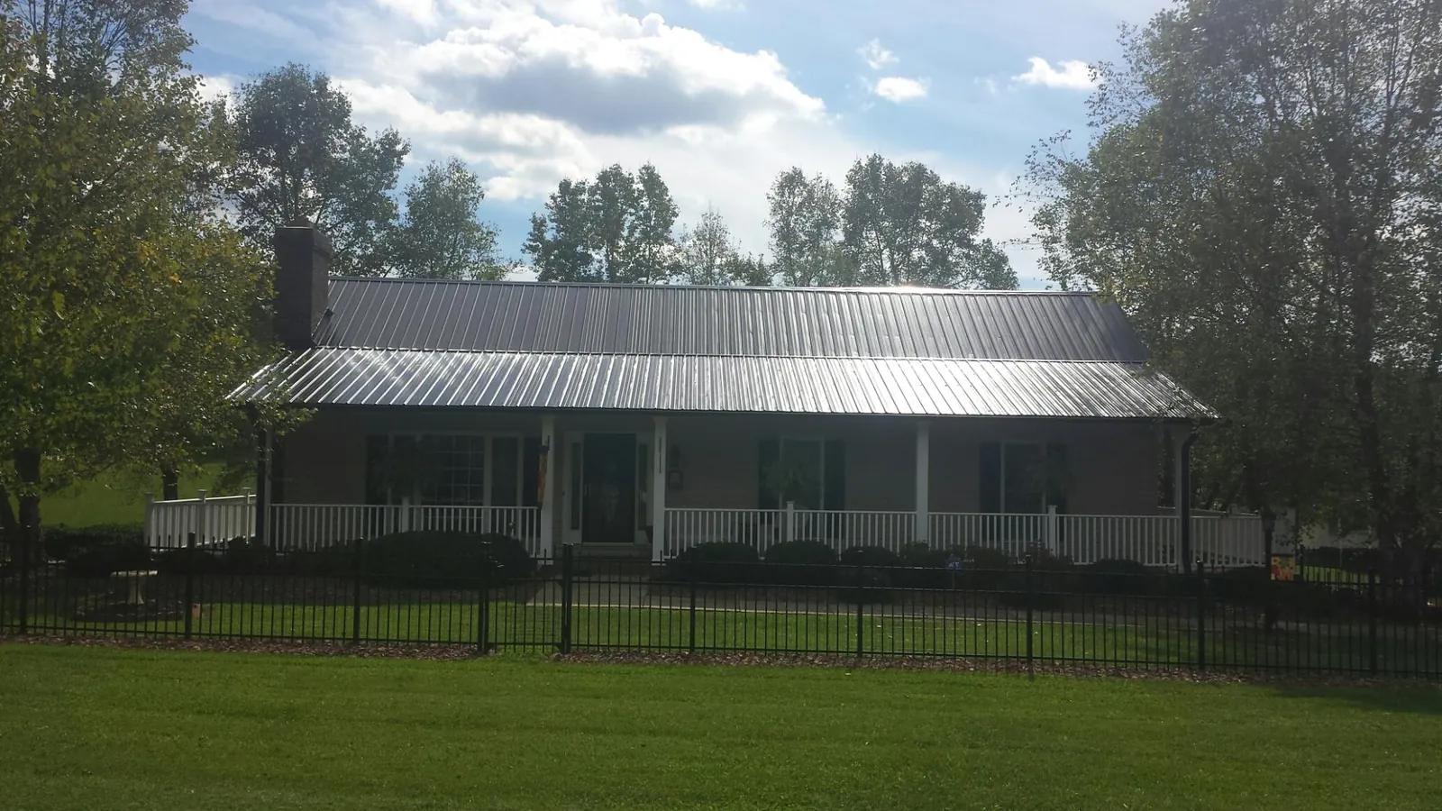 Gray metal roof on a brick ranch with a full width front porch — Gutter Guard Installation work by our crew in Dundas