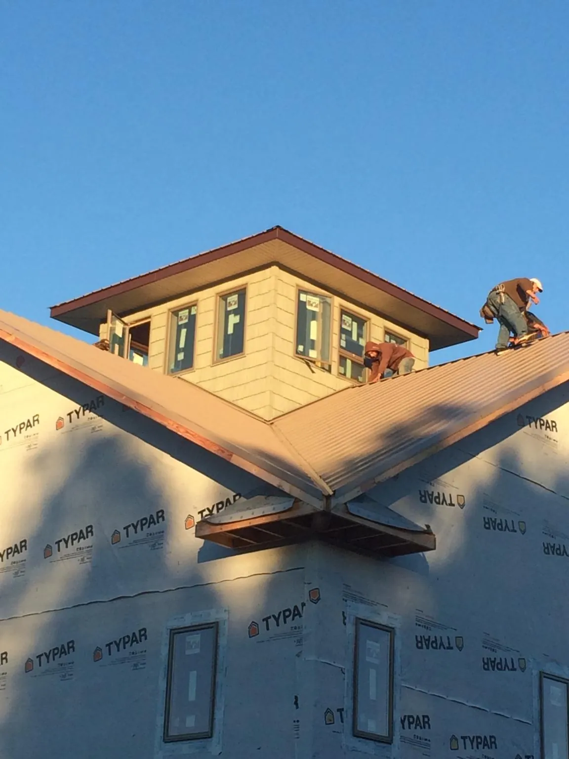 Roofers working around a rooftop cupola on a new metal roof at sunset — Roof Waterproofing in Dundas by Roofing Brothers
